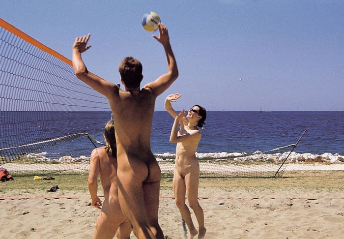 Grupa naturystów, gra w siatkówkę plażową. 
