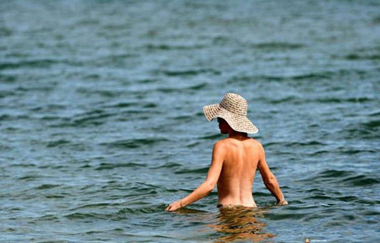 Nudystka w kapeluszu zażywa morskiej kąpieli
