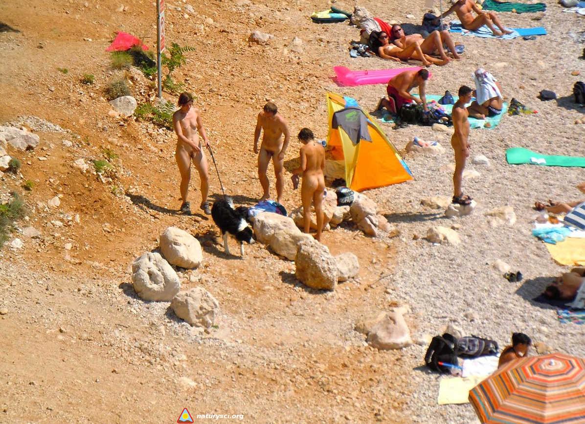 Kilku naturystów na plaży latem.